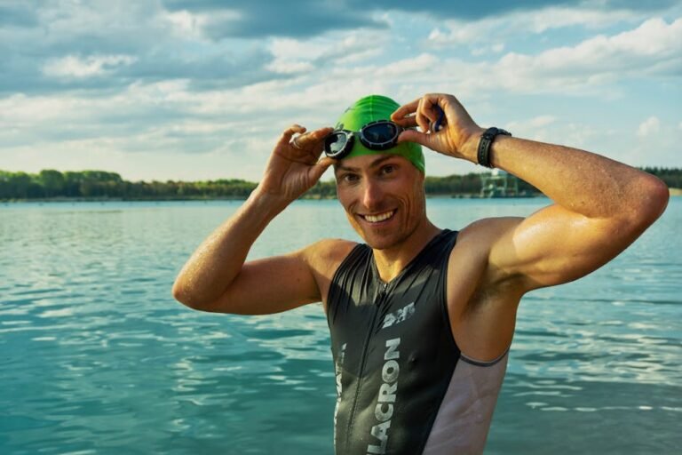 A focused triathlete standing on the beach, holding multiple pairs of open water swimming goggles trying to choose the perfect fit