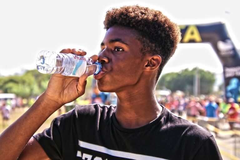 Triathlete eating an energy gel and drinking electrolytes on the beach before an open water swim