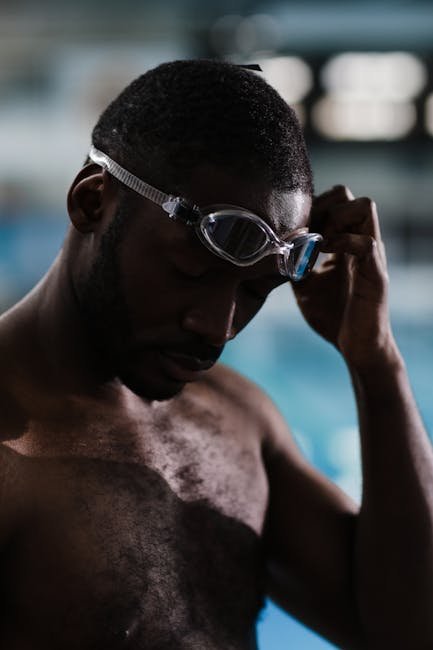 A triathlete putting on a pair of clear prescription swim goggles with focus on the optical lenses