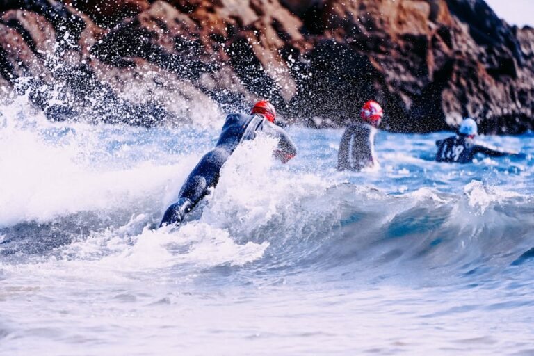 A triathlete wearing a premium black neoprene triathlon wetsuit running into the ocean waves