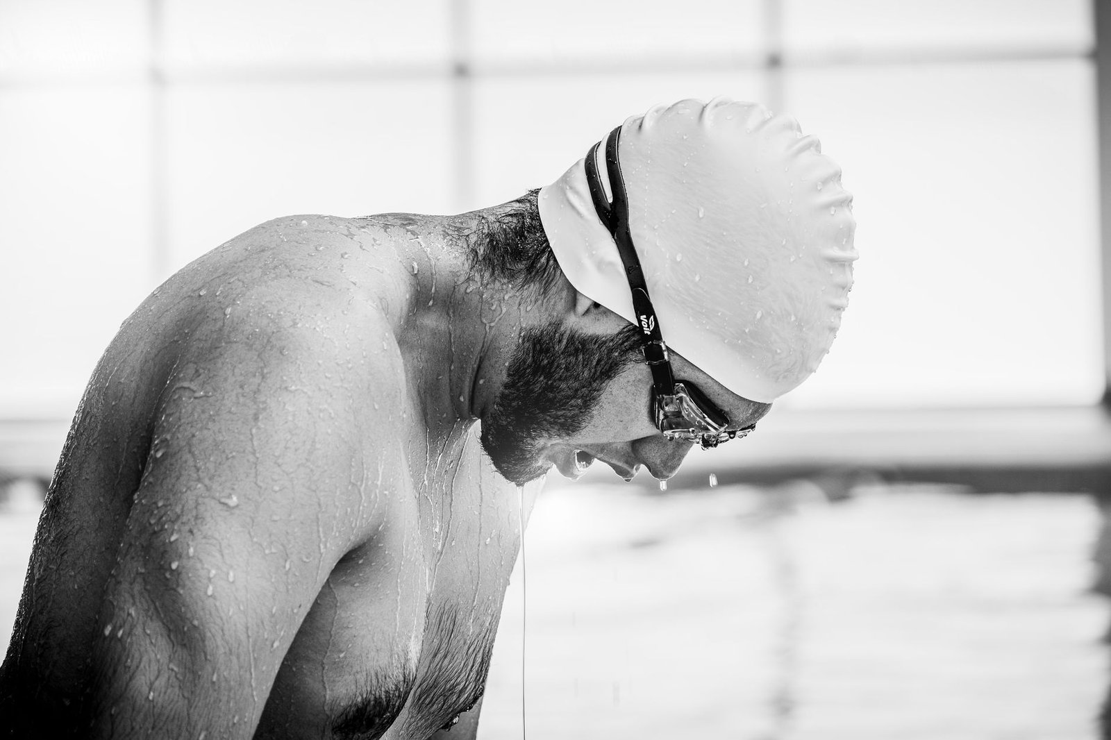 Open water swimmer choosing between clear smoke and mirrored swim goggles before a lake swim