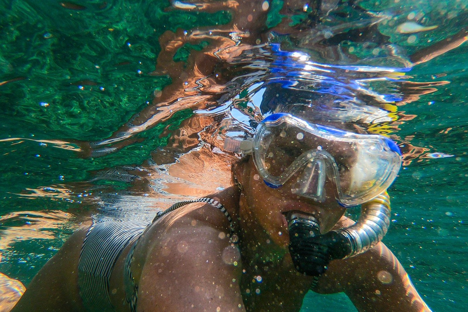 Open-water swimmer wearing goggles near a lake shoreline
