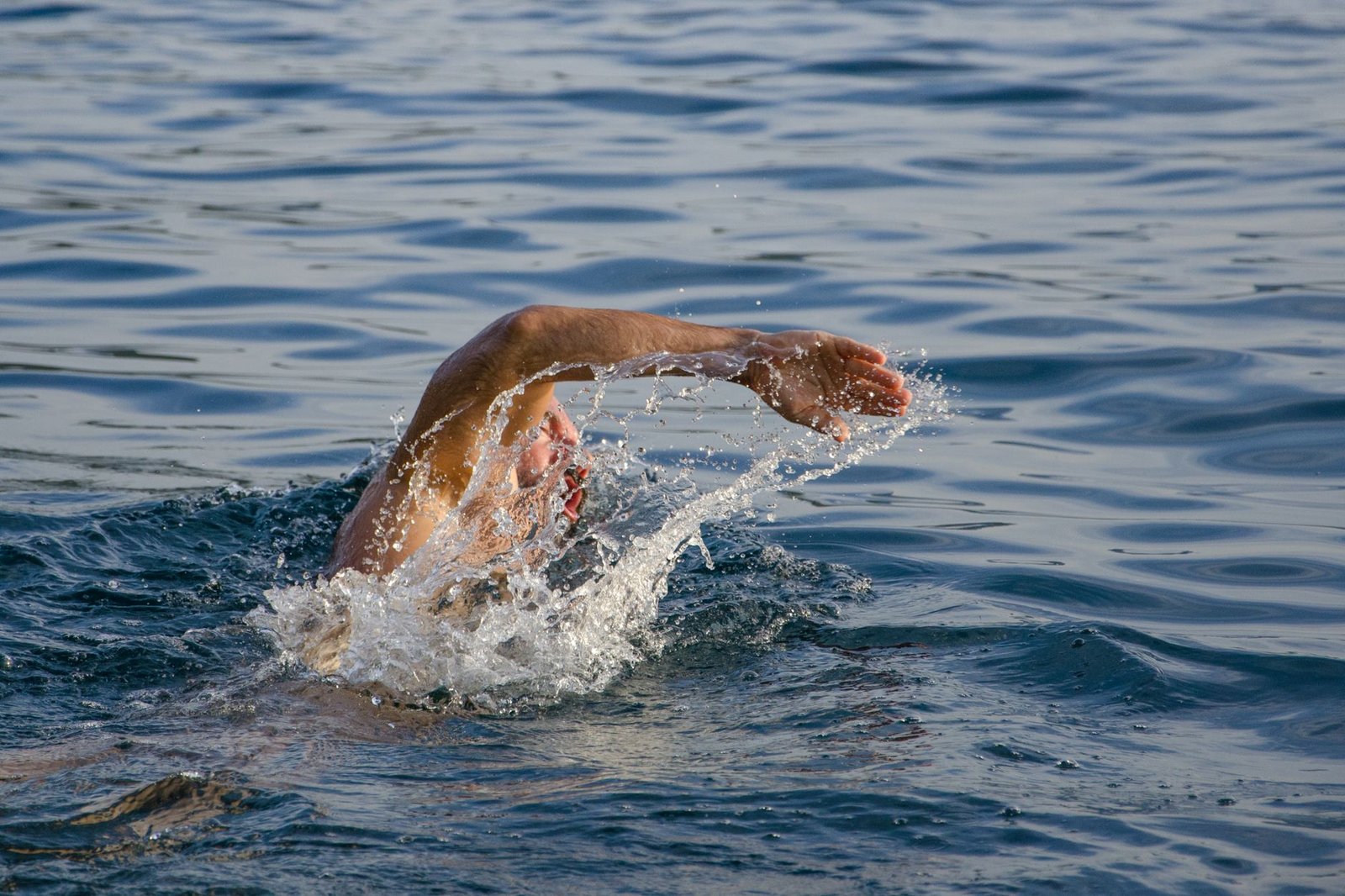 Open-water swimmer wearing goggles in bright side glare